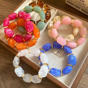 Colorful acrylic irregular oval bead bracelets displayed in a vintage wooden jewelry tray