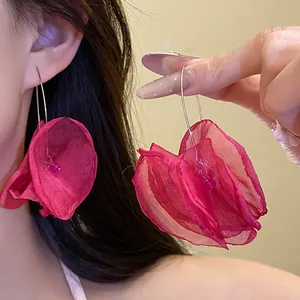 Detailed view of large red chiffon flower hoop earrings worn by an Asian model.