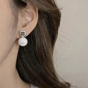 Detalle de un pendiente plateado con perla redonda de resina blanca muy elegante