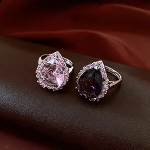 Elegante birnenförmige Zirkonringe in Rosa und Lila mit Halo-Fassung auf Luxushintergrund