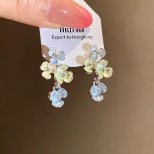 Primo piano di delicati orecchini floreali con smalto pastello e strass scintillanti.