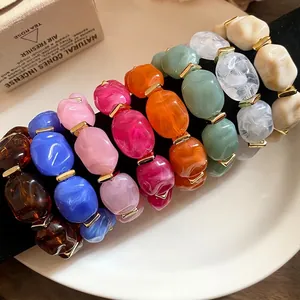Colorful irregular oval acrylic bead bracelets with gold-tone spacers on display