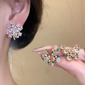Close-up of pink zircon butterfly and flower stud earrings with delicate gold setting