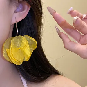 Close-up of vibrant yellow chiffon flower drop earrings elegantly worn by an Asian model