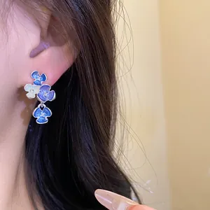 Dettaglio di eleganti orecchini a lobo floreali in smalto blu con brillanti strass