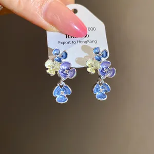 Vista dei dettagli di eleganti orecchini a fiore con petali blu, viola e gialli.