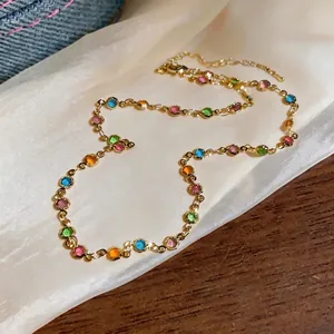 Dainty gold chain necklace featuring multi-colored round resin charms on silk background