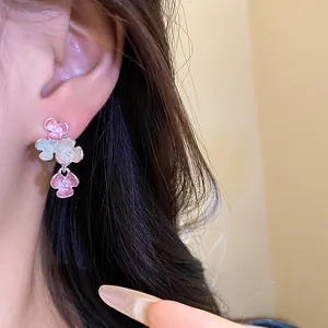Eleganti orecchini a lobo a fiori in stile coreano con piccoli strass su una modella