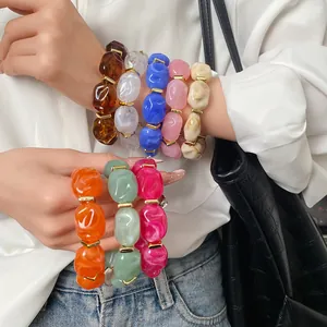 Detailed view of vibrant acrylic irregular geometric oval bracelets stacked on a model