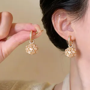 Primo piano di eleganti orecchini placcati oro 18k con occhio di gatto e zirconi