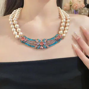 Dettaglio di una collana di perle a doppio filo con ciondolo in strass colorati.