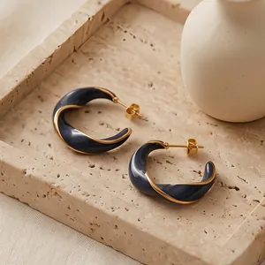 Dettaglio di orecchini a C intrecciati con smalto scuro e finitura placcata oro 18K.
