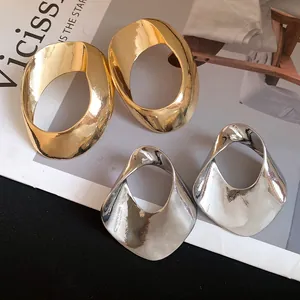 Detailed view of oversized geometric hollow earrings in gold and silver finish