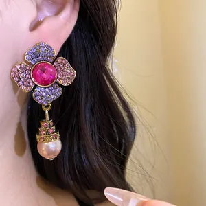 Vista dettagliata di orecchini a fiore vintage con strass rosa e pendente di perla rosa