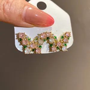 Close-up of a vintage butterfly stud earring with pink and green zircons on a white card