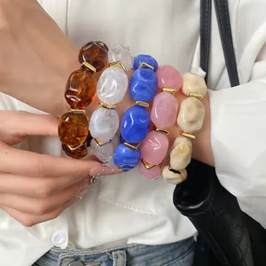 Detailed close-up of colorful irregular geometric acrylic oval bracelets on arm.