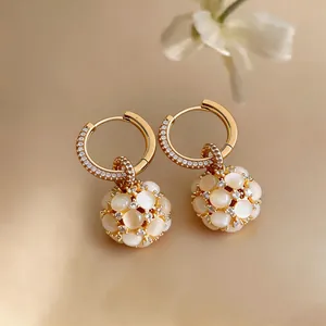 Primo piano di orecchini a cerchio placcati in oro 18k con zirconi e pietre occhio di gatto