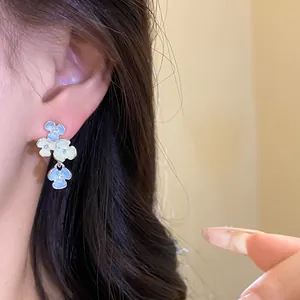 Primo piano di eleganti orecchini pendenti a fiori blu in stile coreano su una modella.
