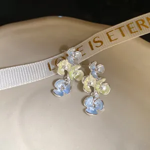 Primo piano di orecchini a fiore con smalto blu e giallo e strass lucidi