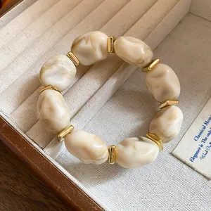 Close-up of a vintage-style acrylic irregular geometric oval bracelet with golden accents.