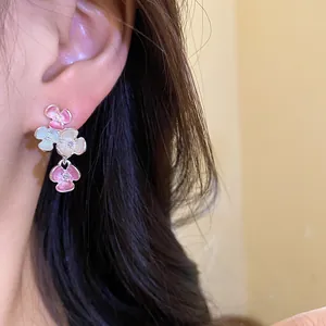 Primo piano di dolci orecchini floreali in stile coreano con strass indossati all'orecchio.