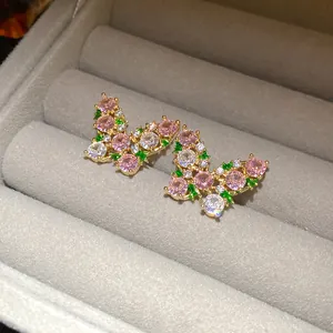 Close-up of butterfly stud earrings with pink, green, and clear zircon stones.