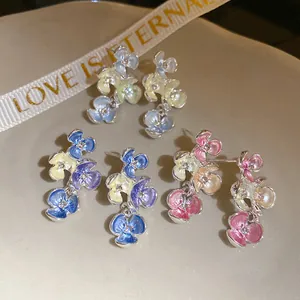 Dettaglio macro di orecchini a lobo a fiore stile coreano con strass e petali colorati