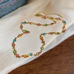 Close-up view of a dainty gold-toned necklace featuring colorful round resin stones