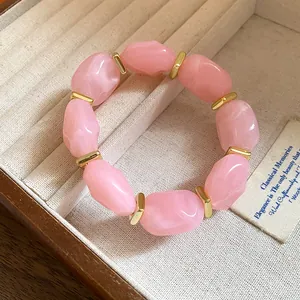 Close-up of pink irregular acrylic beads and gold spacers on a jewelry tray
