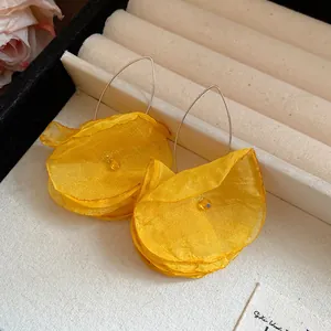 Close-up detail of yellow chiffon flower earrings featuring multi-layered fabric petals