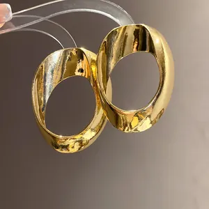 Macro view showing the metallic texture and twisted geometric design of gold earrings