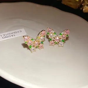 Detailed macro view of colorful butterfly zircon stud earrings with pink and green stones