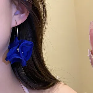 Detailed close-up showing the soft texture of elegant blue chiffon flower drop earrings on a model
