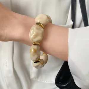 Detailed view of a chunky irregular acrylic bracelet with marble texture and gold accents