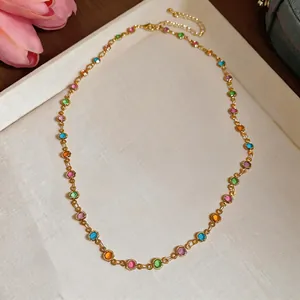Colorful resin round bead necklace on gold chain displayed on a decorative tray.