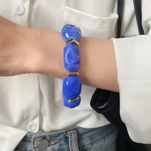 Close-up view of a stylish blue acrylic bracelet with irregular oval beads on a wrist