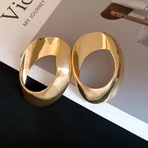 Detailed view of large hollow geometric oval earrings in shiny gold finish