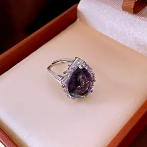 Detailansicht eines eleganten lila Zirkonrings in Tropfenform in einer Geschenkbox