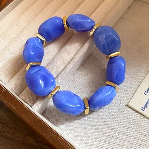 Macro view of blue acrylic irregular bead bracelet with gold metal spacers in jewelry box