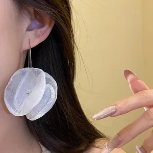 Detailed close-up showing a white chiffon flower petal earring worn on the ear.