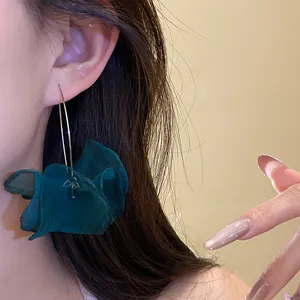 Close-up of a dark green chiffon flower earring worn on ear showing soft petal texture.
