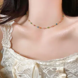 Close-up view of a gold choker necklace with colorful resin round beads on a model.