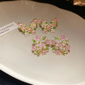 Close-up detail of vintage butterfly and four-leaf clover earrings with pink zirconia stones