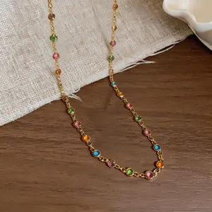 Detail view of a dainty gold-toned chain necklace with colorful circular resin stones