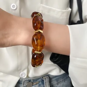 Detailed view of amber acrylic irregular geometric oval bracelet worn on a female wrist