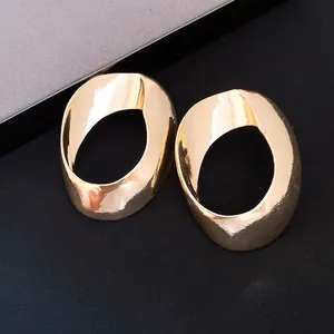 Close-up view of elegant gold-tone geometric hollow earrings with a unique twisted circular design.