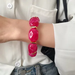 Close-up of chunky magenta acrylic irregular oval bead bracelet with gold spacers