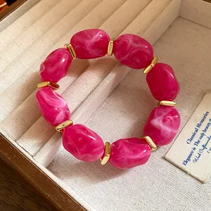 Close-up of pink marbled acrylic beads and gold spacers on a chic statement bracelet