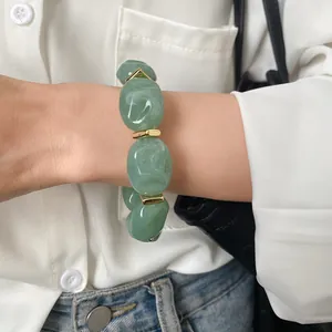 Detailed view of chunky green acrylic bracelet featuring irregular beads and gold metal spacers