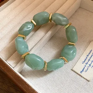 Detailed view of green marble-patterned acrylic beads and golden spacers on a bracelet.